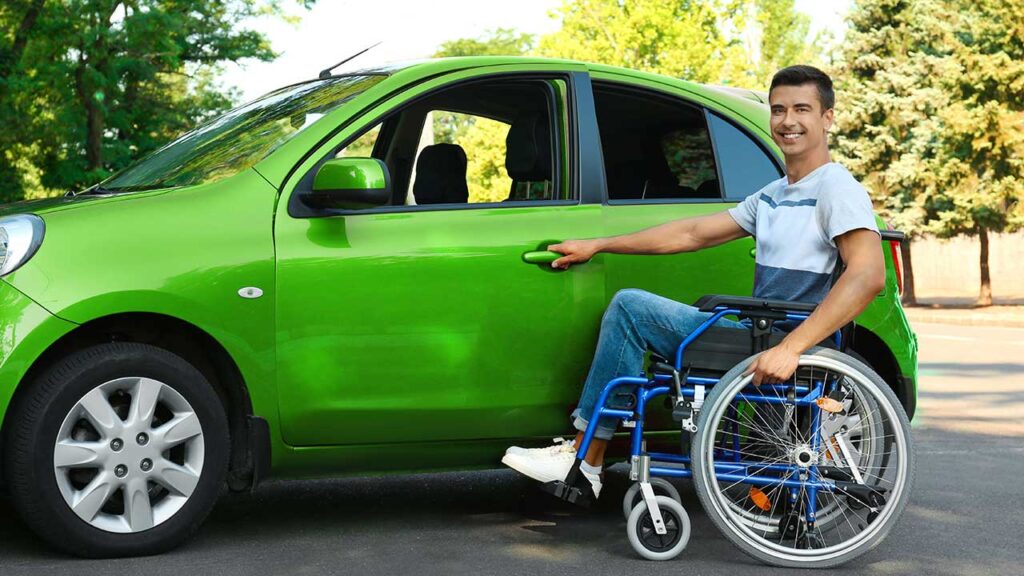 Carro PCD: Quem tem direito a adquirir esse custo-benefício? 6 Homem com cadeira de rodas prestes a entrar em um carro verde