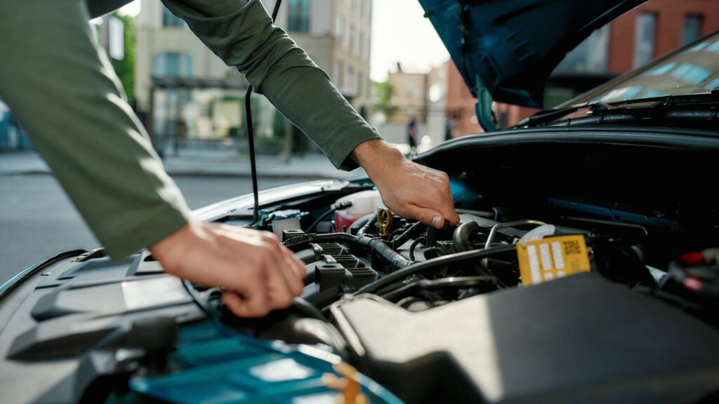 carros com manutenção barata - carro com capo aberto enquanto mao masculina mexe no motor - Descubra como equilibrar depreciação x manutenção