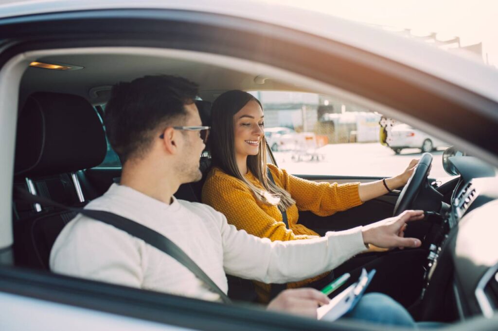 Direção defensiva: o que é e quando usá-la 4 Seguro do carro por quilômetro rodado - homem e mulher felizes dentro de um carro - curso de direção defensiva