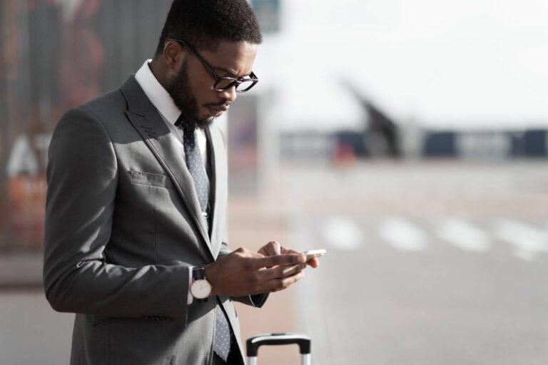 Manual do Lojista 2 como atrair clientes pelas redes sociais - homem segurando o celular na rua
