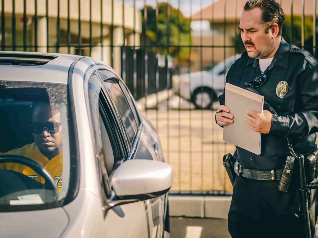 Curso de reciclagem de CNH: tudo o que você precisa saber 4 Imagem de um guarda aplicando uma multa em uma pessoa que está em um carro.
