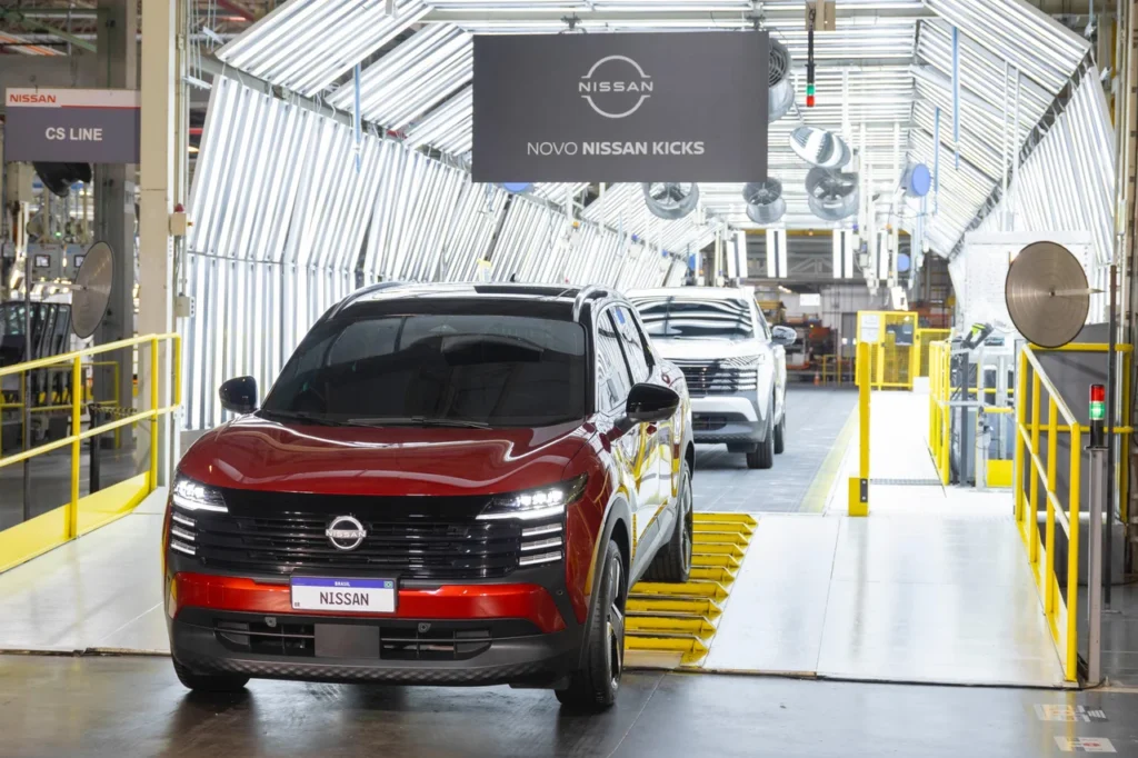 Nissan inicia produção do Novo Kicks em Resende (RJ) 2 Novo Nissan Kicks vermelho lidera fila de carros saindo da linha de produção, sob o letreiro “Novo Nissan Kicks”