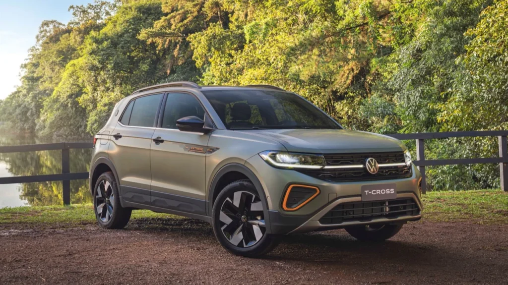 Volkswagen T-Cross Extreme visto de frente e lateral em ambiente natural, estacionado próximo a uma cerca de madeira com lago e árvores ao fundo
