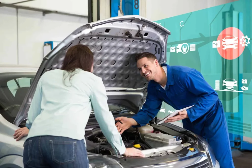Motor ciclo Miller: como funciona, vantagens e principais desafios 2 Mecânico sorridente conversa com cliente enquanto verifica o motor de um carro em uma oficina, representando a importância do histórico de revisões para a manutenção preventiva - motor ciclo miller