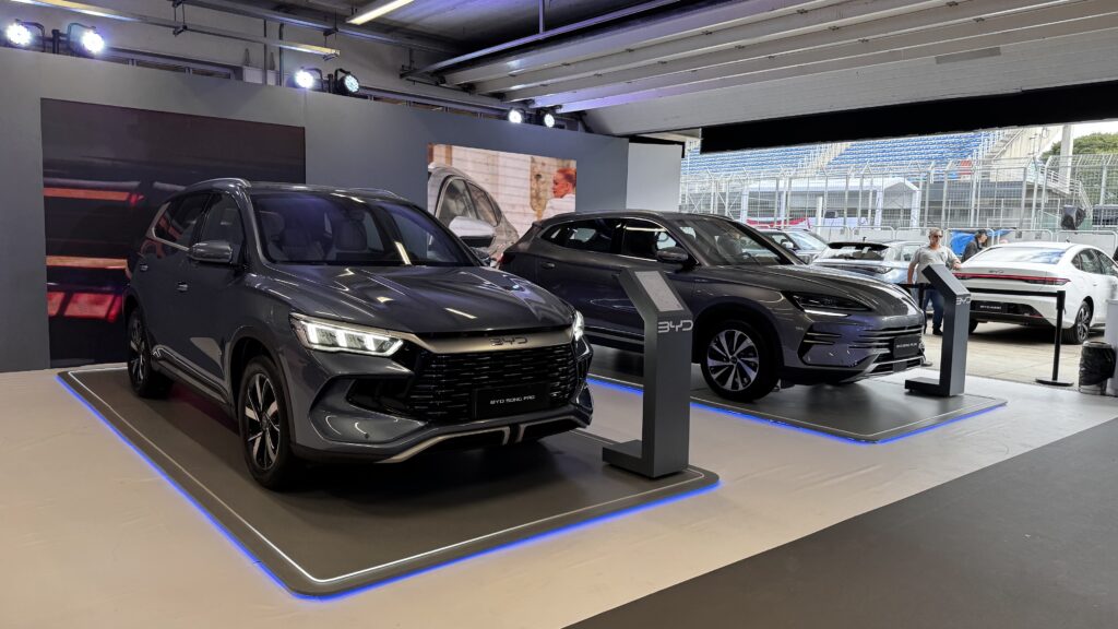 BYD no Festival Interlagos: liderança, tecnologia e produção 3 Feira BYD com exposição de veículos elétricos e híbridos, incluindo os modelos BYD Song Pro e BYD Seal U, em estande iluminado com design moderno e informativo.